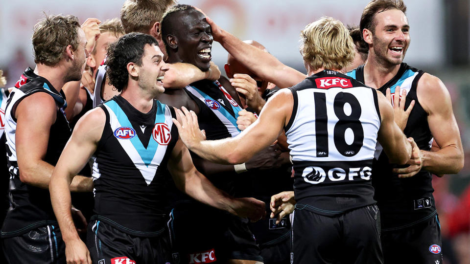 Port Adelaide players celebrate around teammate Allir Aliir.