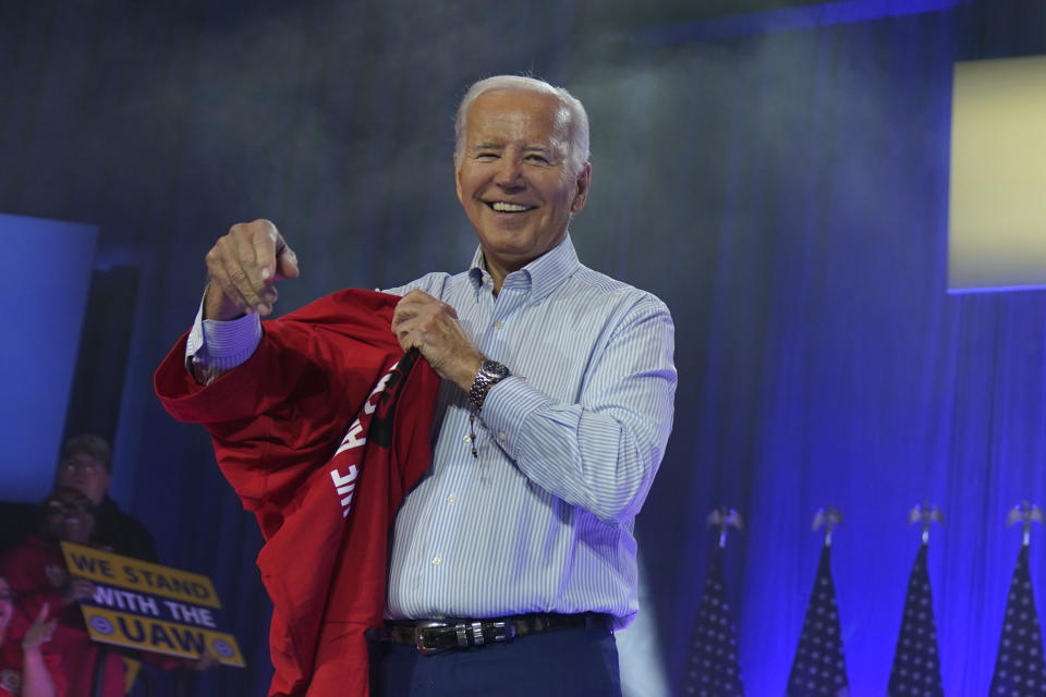 President Joe Biden puts on a UAW Local 1268 shirt before speaking to United Auto Workers at the Community Building Complex of Boone County, Thursday, Nov. 9, 2023, in Belvidere, Ill. (AP Photo/Evan Vucci)