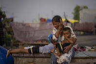 Rekha Devi, a 30-year-old farm worker, holds her son in her lap next to her temporary shelter on an under construction overpass after her family evacuated the flooded banks of the Yamuna River in New Delhi, India, Wednesday, Aug. 9, 2023. Devi, her husband and their children fled as July's record monsoon rains triggered flooding that killed more than 100 people in northern India, displaced thousands and inundated large parts of the capital city. (AP Photo/Altaf Qadri)