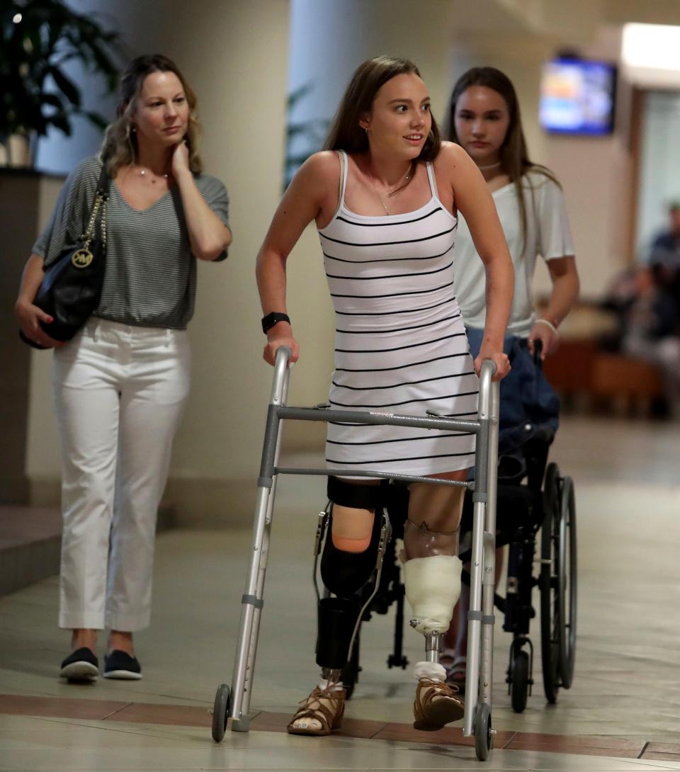 This photo taken Feb. 22, 2019, shows Stefanie Schaffer, 22, center, her mom Stacey Bender, left, and sister, Brooke,right, who were brought to Broward Health Medical Center in Fort Lauderdale, Fla., after a boat explosion in the Bahamas in July, return to surprise the doctors and staff who helped saved Stefanie's her life. (Carline Jean /South Florida Sun-Sentinel via AP)