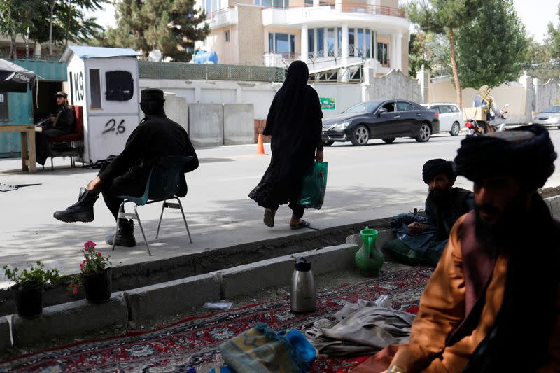 An Afghan woman walks among Taliban soldiers at a checkpoint in Kabul