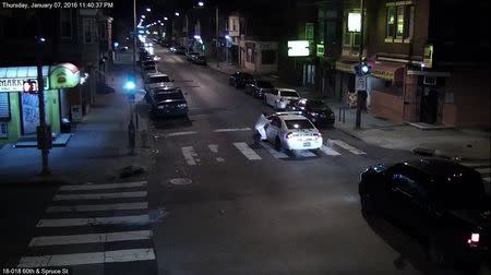 A still image from surveillance video shows a gunman (L) approaching a Philadelphia Police vehicle in which Officer Jesse Hartnett was shot shortly before midnight January 7, 2016 in Philadelphia, Pennsylvania this Philadelphia Police Department image released on January 8, 2016. REUTERS/Philadelphia Police Department/Handout