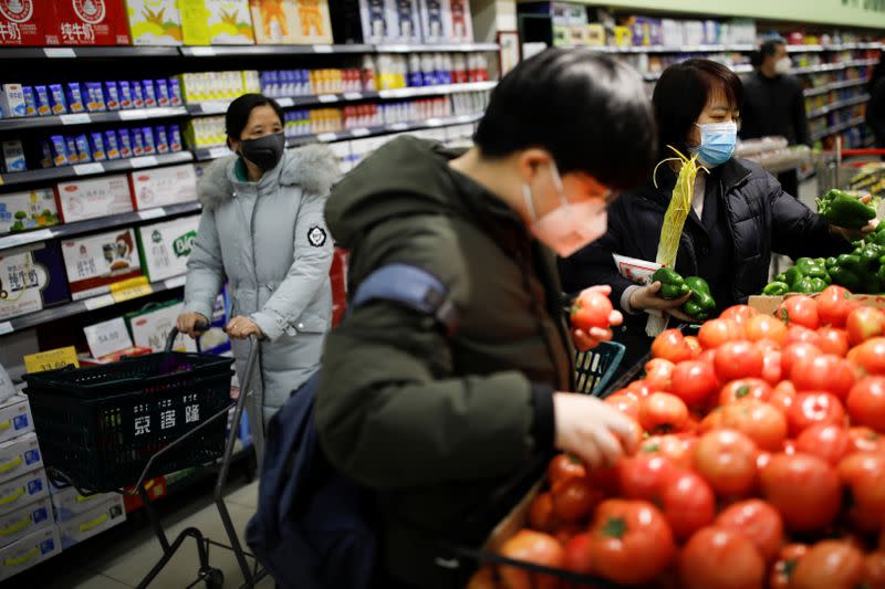 People wearing face masks look for products at a supermarket, as the country is hit by an outbreak of the new coronavirus, in Beijing