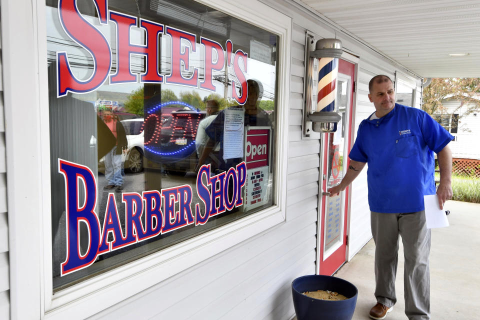 Brad Shepler, a barber who resumed cutting hair despite it being prohibited under Pennsylvania Gov. Tom Wolf's coronavirus shutdown orders, walks out of his barber shop to hold a new conference with local state lawmakers, Thursday, May 14, 2020 in Enola, Pa. Shepler also received a warning letter from the state's licensing agency. (AP Photo/Marc Levy)