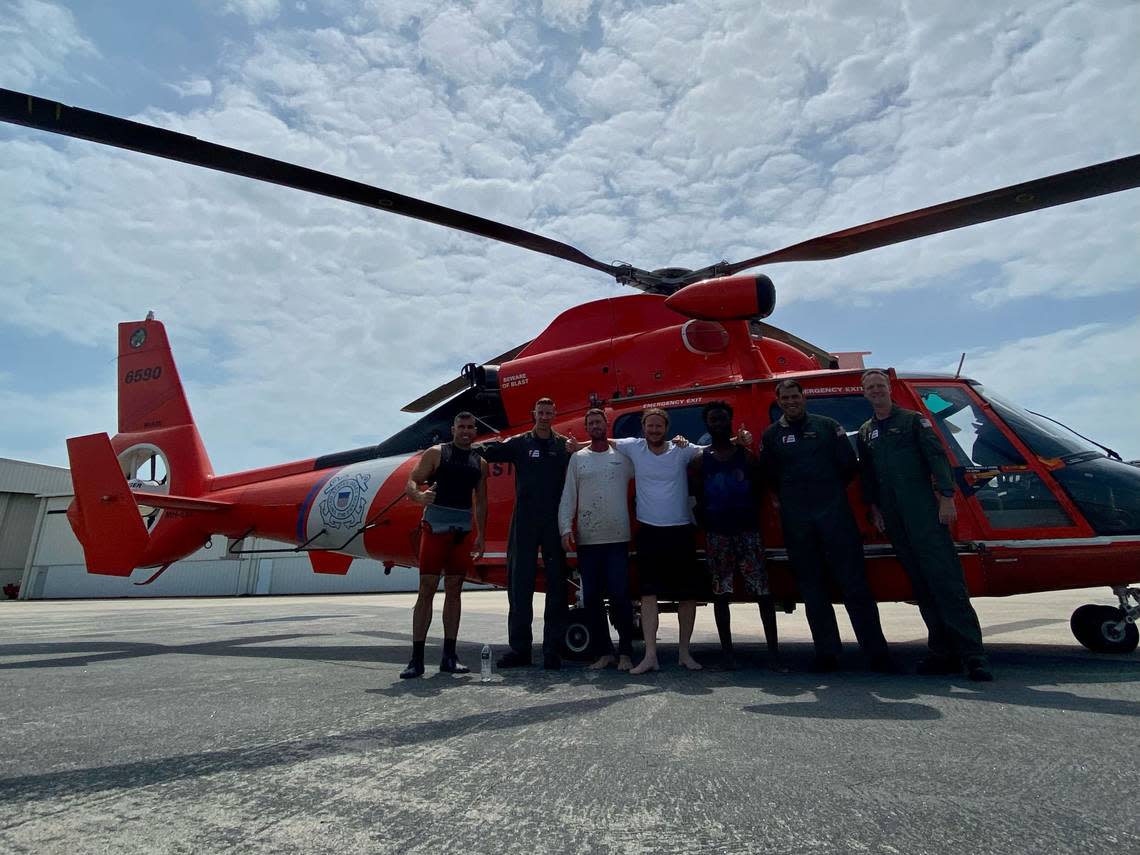 A U.S. Coast Guard Air Station MH-65 Dolphin helicopter crew poses with three rescued men after their boat sunk near Dry Tortugas National Park, Florida, on April 30, 2023. U.S. Coast Guard