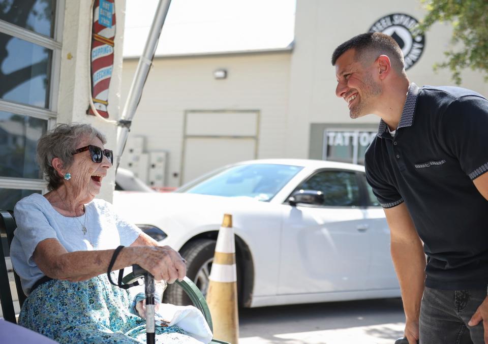 Customer and friend of barber John Gentile Sr., Jacqueline Snow, 97, of Stuart, talks with Gentile's son, John Gentile Jr., during a memorial for Gentile outside of Johnny G's Barber Shop on Wednesday, April 24, 2024, in downtown Jensen Beach. Gentile, 62, died April 18. "My husband died in 2012 and John said he'd cut my hair for the rest of my life for nothing," said Snow. He was known for his "quirky'' barbershop and worked in the area for about 40 years.