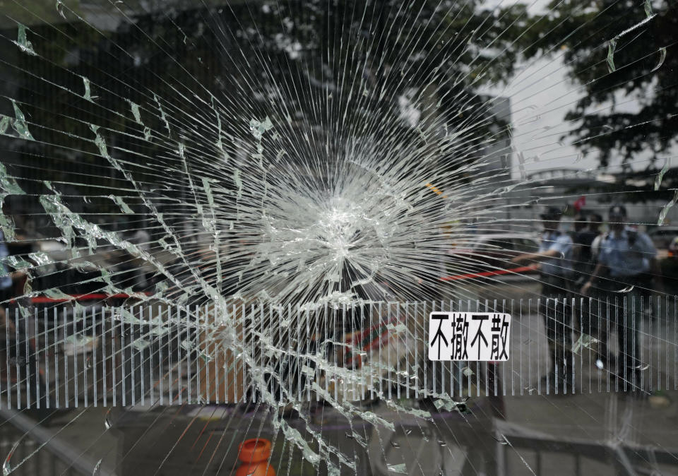 Police officers stand guard near a broken glass outside Legislative Council building in Hong Kong, Tuesday, July 2, 2019. Hundreds of protesters swarmed into Hong Kong's legislature Monday night, defacing portraits of lawmakers and spray-painting pro-democracy slogans in the chamber before vacating it as riot police cleared surrounding streets with tear gas and then moved inside. The words read " not leave, not withdraw." (AP Photo/Vincent Yu)