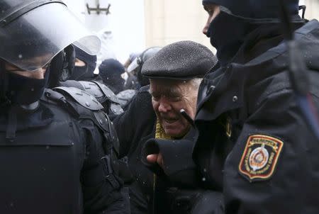 A man, surrounded by law enforcement officers, reacts during a gathering, denouncing the new tax on those not in full-time employment and marking the 99th anniversary of the proclamation of the Belarussian People's Republic, in Minsk, Belarus, March 25, 2017. REUTERS/Vasily Fedosenko