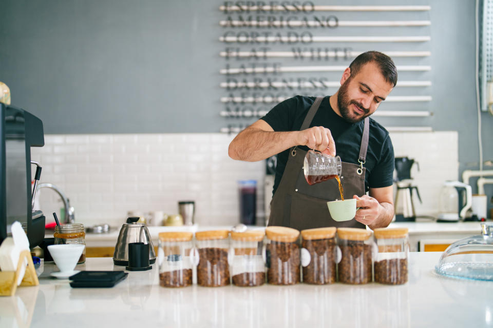 man pouring coffee behind the counter