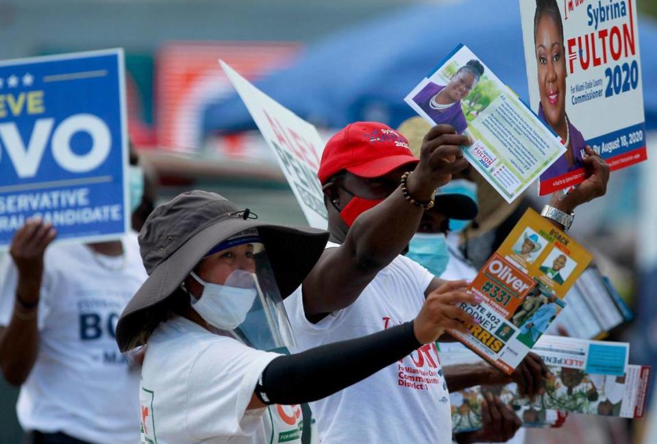 Campaign volunteers hold up signs and hand-out campaign literature as motorists arrive at the North Dade Library to vote early during the local primaries. On Sunday, August 16, Faith in Florida and Florida Rights Restoration Coalition came together and hosted Souls to the Polls Parade in Miami-Dade County and caravan to the North Dade Library in Miami Gardens, Florida .