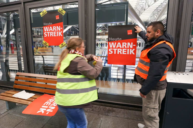 Strikers and union representatives stick posters with the words "Warning strike!" on the windows at Terminal 2 of Hamburg Airport, one of 11 major German airports that have started a one-day strike. Bodo Marks/dpa