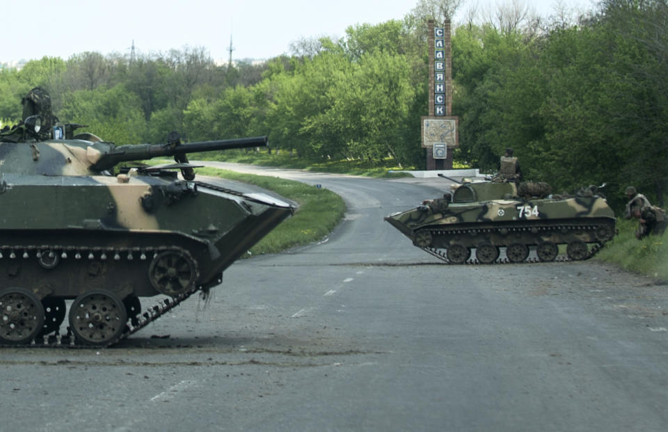 A Ukrainian APCs are parked blocking a road outside the town of Slovyansk, eastern Ukraine, Sunday, May 4, 2014. Ukrainian authorities are currently seeking to form a security cordon around the town. They have repeatedly claimed victories in capturing checkpoints surrounding the city, although such boasts have often proven overstated. (AP Photo/Evgeniy Maloletka)