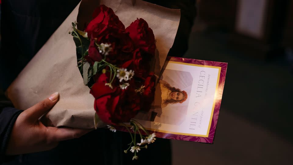 Maz George holds flowers and a pamphlet after Gentili's funeral. "As a former Catholic myself, I've never seen so many queer people in church,” they said. - Laura Oliverio/CNN