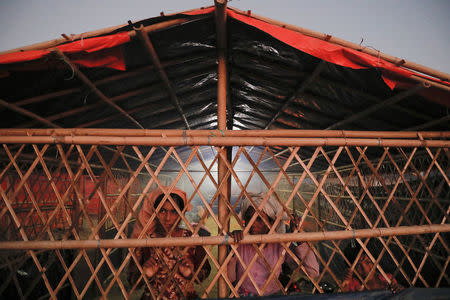 Rohingya refugees look from inside a kitchen of the camp for widows and orphans inside the Balukhali camp near Cox's Bazar, Bangladesh, December 4, 2017. More than 230 women and children live at a so-called widows camp built by fellow refugees with the help of donor funds for Rohingya widows and orphans to offer them better protection and shelter. REUTERS/Damir Sagolj