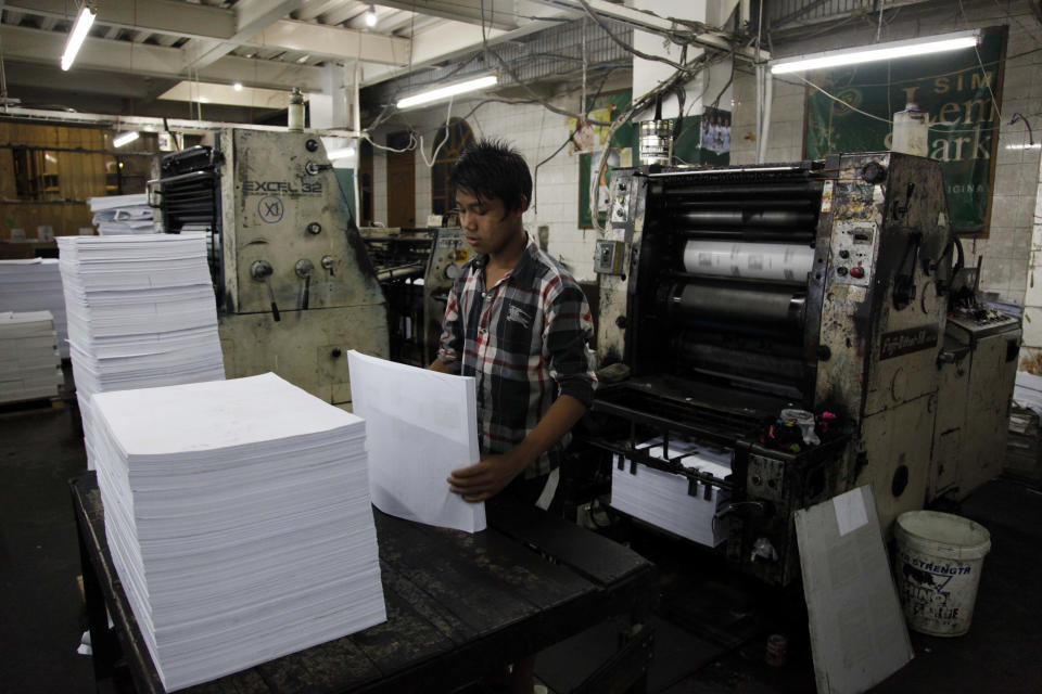 In this photo taken on March 11, 2014, a print worker arranges paper at their printing press of “The Golden Fresh Land Daily” newspaper, in Yangon, Myanmar. One year after publishers and editors took advantage of a decision by the country's nominally civilian government to lift a half-century-old ban on private dailies, the feeling of euphoria is fading. The struggle to compete with state-owned papers for advertisers and circulation have made it impossible for many to forge on. Golden Fresh Land, published its last edition Wednesday, March 12. It is the first well-known private daily to fold, but 11 others that are still publishing also appear to be struggling.(AP Photo/Khin Maung Win)