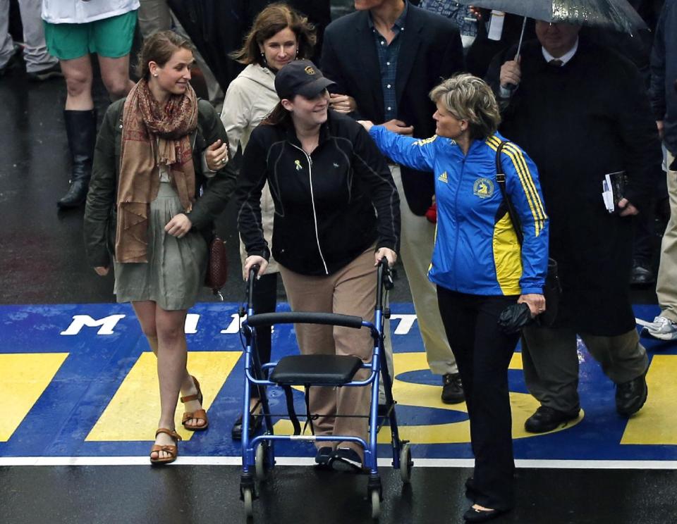 2013 Boston Marathon bombing survivor Erika Brannock, a pre-school teacher from the Baltimore area, and her mother, Carol Downing, at right, walk across the Marathon finish line after a remembrance ceremony on Boylston Street in Boston, Tuesday, April 15, 2014. (AP Photo/Elise Amendola)