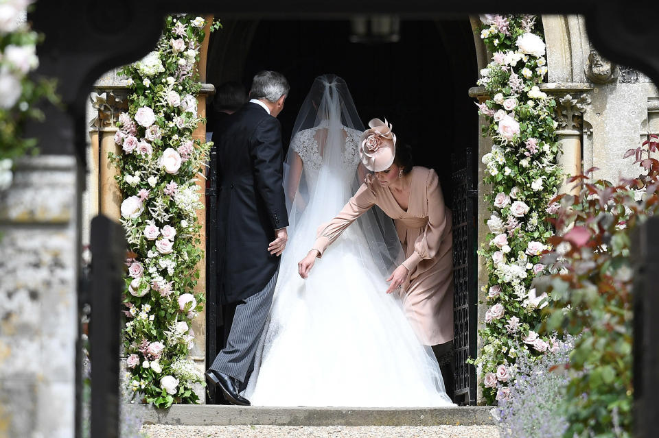 Catherine, Duchess of Cambridge adjusts Pippa Middleton's dress.
