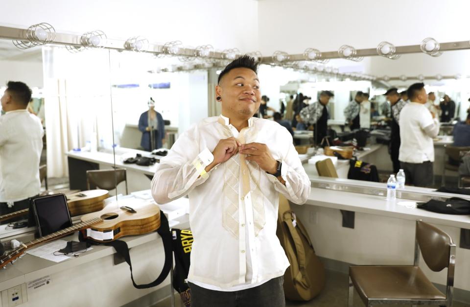 Singer-songwriter AJ Rafael, the evening's host, buttons his shirt.