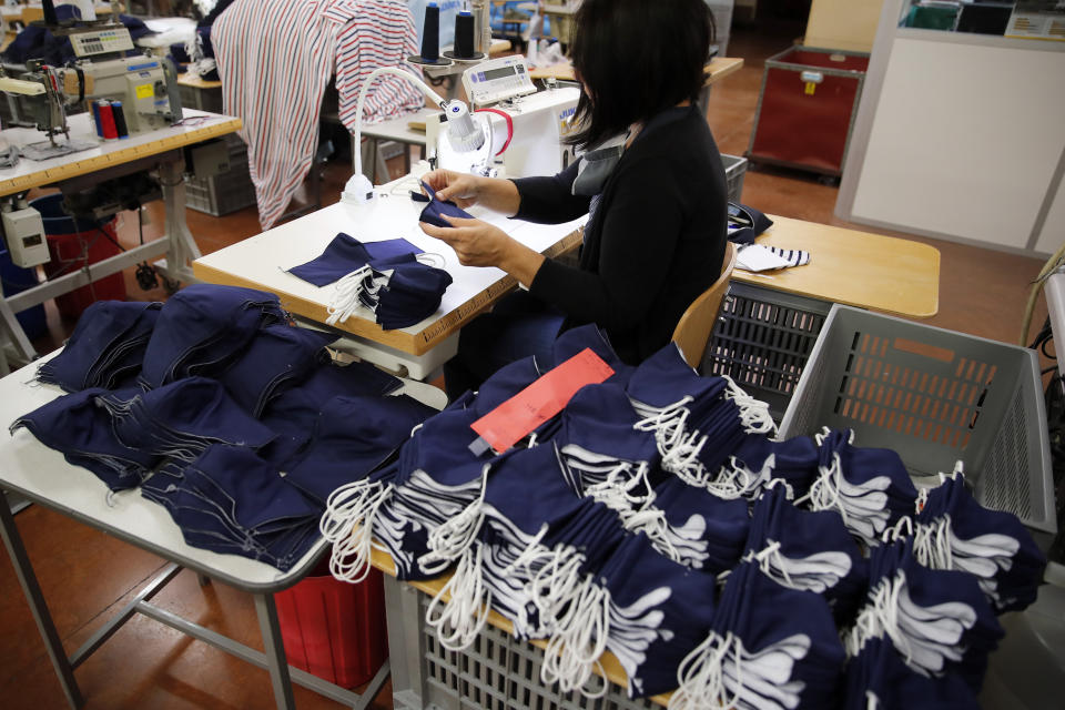 In this Friday, June 12, 2020 photo, an employee sews face protective masks in Chanteclair Hosiery, a French knitwear clothing manufacturer in Saint Pouange, east of Paris. The French praised the altruism of luxury goods companies such as LVMH, Kering and Chanel for diverting their production facilities to make millions of face masks for the public during the peak of their country's coronavirus outbreak. Now, the companies that helped France avoid a dangerous shortage say they need help unloading a surplus of 20 million washable masks. (AP Photo/Francois Mori)