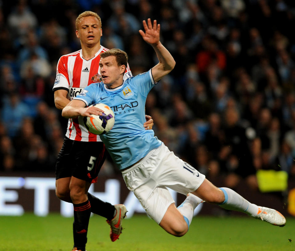 Manchester City's Edin Dzeko is tackled by Sunderland's Wes Brown during the English Premier League soccer match between Manchester City and Sunderland at The Etihad Stadium, Manchester, England, Wednesday, April 16, 2014. (AP Photo/Rui Vieira)
