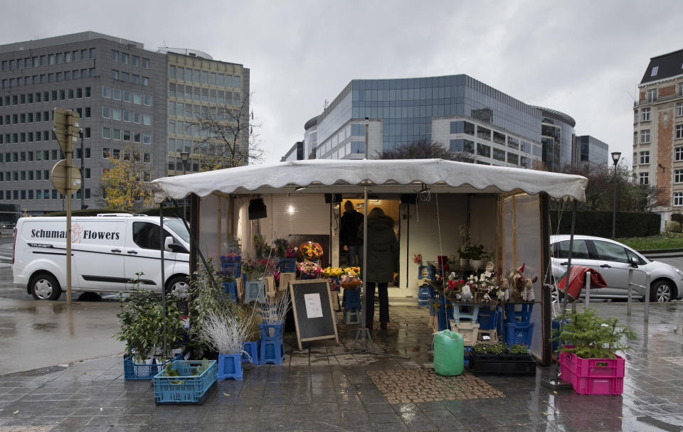 A woman talks to a flower seller outside EU headquarters in Brussels, Thursday, Dec. 24, 2020. European Union and British negotiators worked through the night and into Christmas Eve in the hopes of putting the finishing touches on a trade deal that should avert a chaotic economic break between the two sides on New Year's Day. (AP Photo/Virginia Mayo)