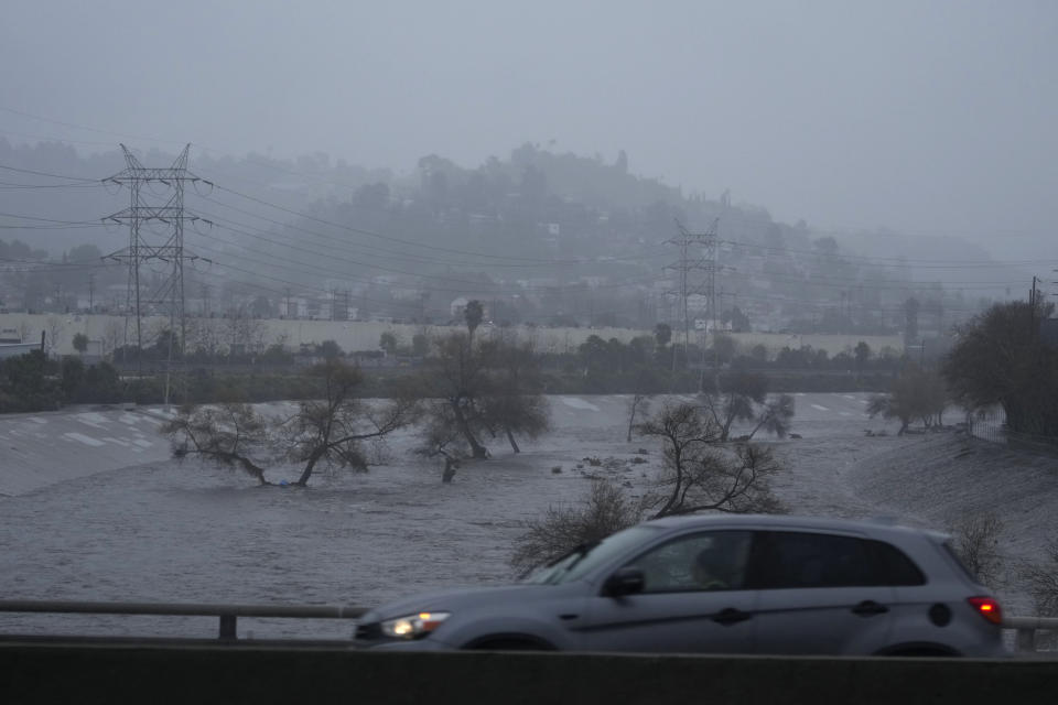 Motorists cross a bridge over the Los Angeles River, carrying stormwater downstream Sunday, Feb. 4, 2024, in Los Angeles. The second of back-to-back atmospheric rivers is drenching Northern California, flooding roads, knocking out power to hundreds of thousands and leading forecasters to warn of possible hurricane-force winds and mudslides as it heads south. (AP Photo/Damian Dovarganes)