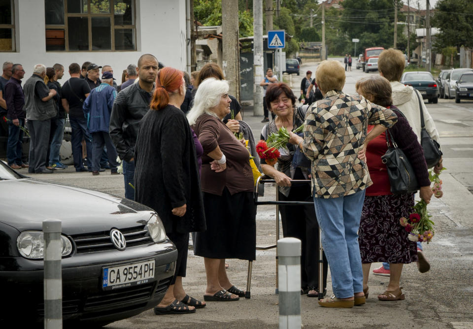 Bulgarians take part in a funeral for victims of a bus crash, in Svetovrachene, Bulgaria, Tuesday, Aug. 28, 2018. A Bulgarian village just outside the capital has held funeral services for 15 of its residents who died in a bus crash over the weekend. Many of the 2,000 residents of Svetovrachene who came to pay final respects on Tuesday were related to the victims of the accident, which killed 17 people when a bus full of religious pilgrims overturned and fell off a highway about 50 kilometers (30 miles) north of Sofia. (AP Photo/Filip Dvorski)