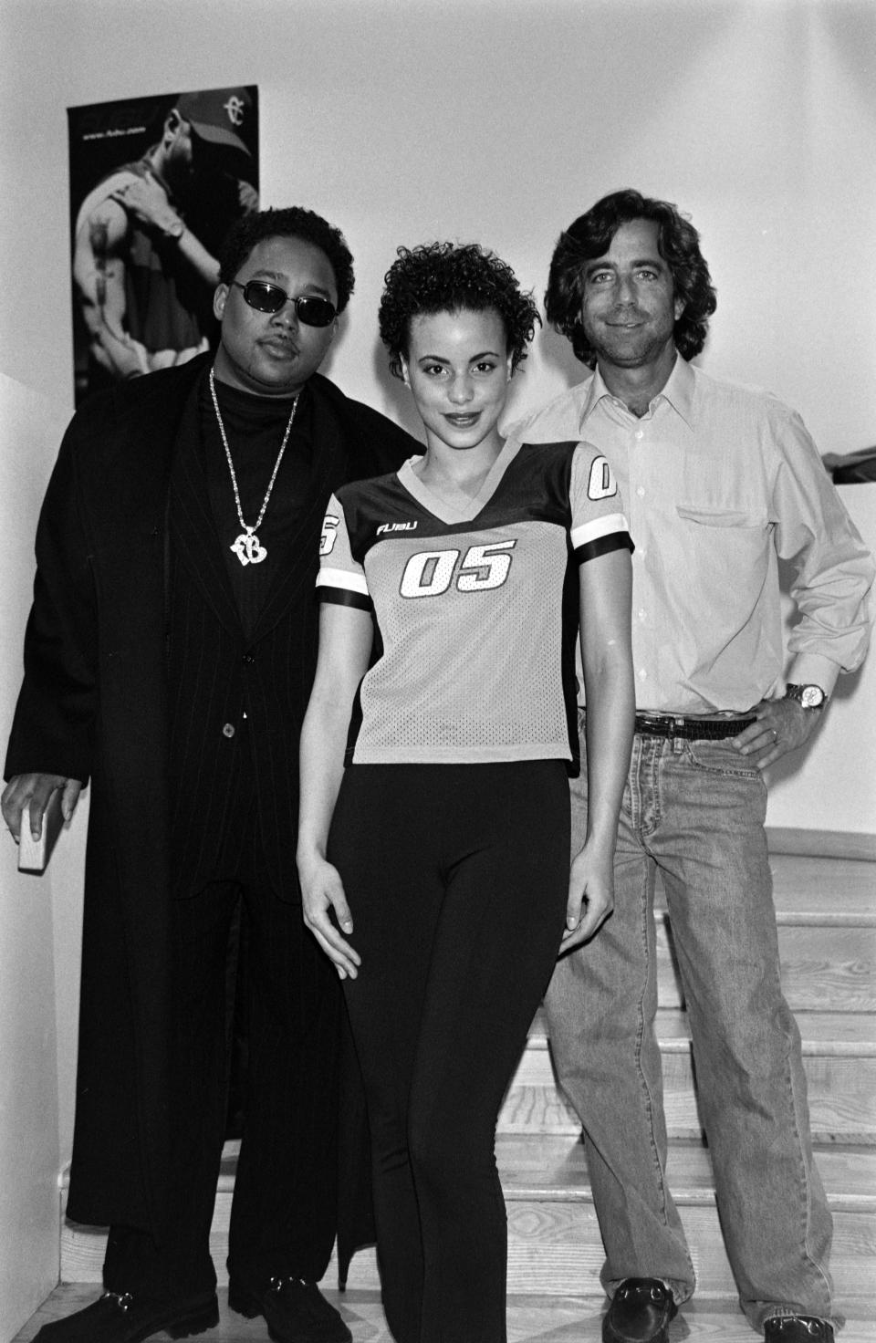Designer-founder Daymond John and Jordache’s Elliott Lavigne pose with a model in a look from Fubu women’s debut sportswear collection for fall 1998. - Credit: WWD