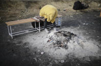 A man sits by the remains of a bonfire after fleeing from the Ukraine near the border crossing in Medyka, Poland, Tuesday, March 1, 2022. Russian shelling pounded civilian targets in Ukraine's second-largest city, Kharkiv, Tuesday and a 40-mile convoy of tanks and other vehicles threatened the capital — tactics Ukraine's embattled president said were designed to force him into concessions in Europe's largest ground war in generations. (AP Photo/Markus Schreiber)