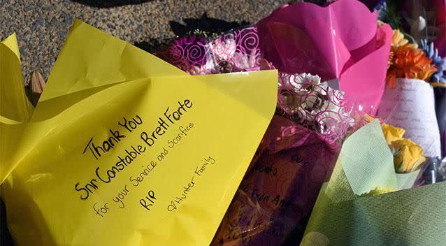 Flowers are laid in memory of a slain police officer at the entrance to the Toowoomba police station. Photo: AAP