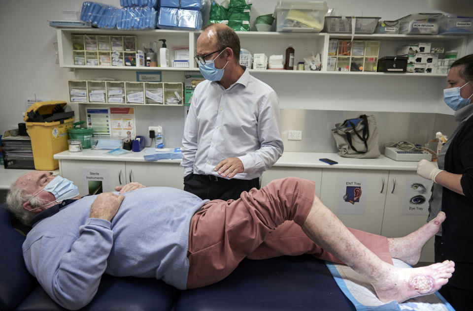 Rob Courtney, un paciente con úlcera de Buruli, es tratado el 12 de marzo de 2021 en Sorrento, Australia, por Daniel O'Brien y la enfermera Donna Beckett. La enfermedad es causada por una especie de bacteria necrosante. (Christina Simons/The New York Times)