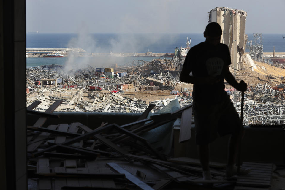 A man stands in a damaged apartment as he looks out at the scene of a massive explosion that hit the seaport of Beirut, Lebanon, Wednesday, Aug. 5, 2020. Residents of Beirut awoke to a scene of utter devastation on Wednesday, a day after a massive explosion at the port sent shock waves across the Lebanese capital, killing at least 100 people and wounding thousands. (AP Photo/Hussein Malla)