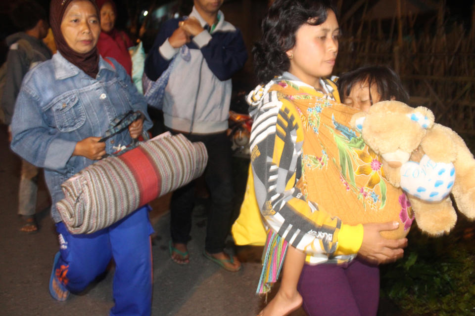 Villagers walk as they are evacuated from their homes on the slope of Mount Kelud in Kediri, East Java, Indonesia, Thursday, Feb. 13, 2014. Indonesia's mount Kelud in densely populated Java Island has erupted, forcing the evacuation of thousands of people. Head of volcano monitoring agency Muhammad Hendrasto, said the mountain in Kediri regency erupted late Thursday, just about 90 minutes after authorities raised its status to the highest level. (AP Photo)