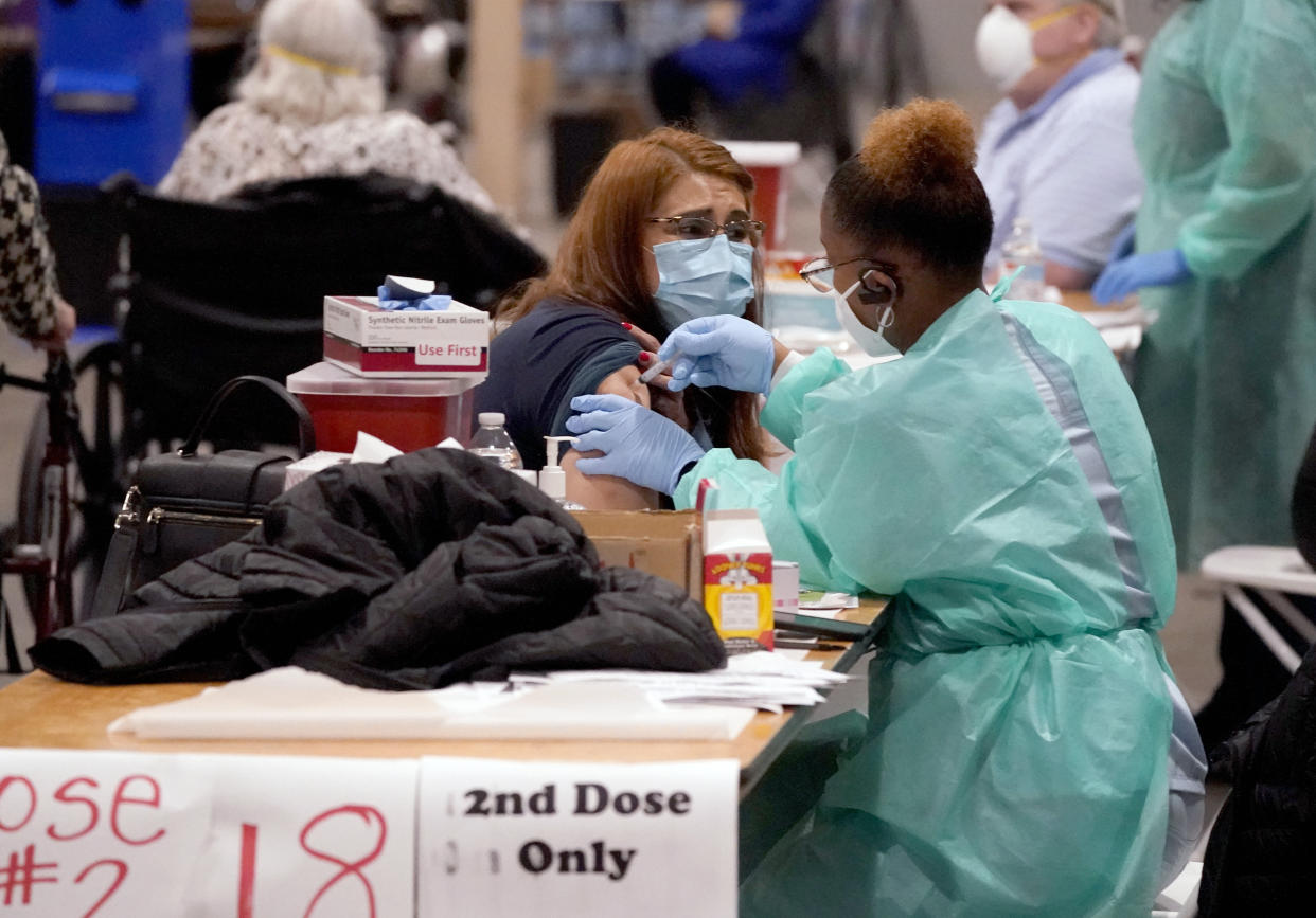 FILE - In this Jan. 20, 2021, file photo, registered nurse, Adele Prieto, left, receives her second dose of the COVID-19 vaccine from Lesia Turner at the Dallas County mass vaccination site at Fair Park in Dallas. As health officials race to vaccinate people across the U.S., the need to give each person two doses a few weeks apart is adding a layer of complexity to the country’s biggest-ever vaccination campaign. (AP Photo/LM Otero, File)