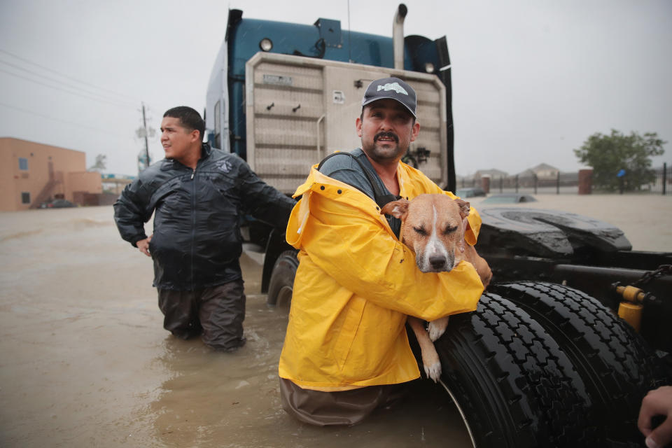 HOUSTON, TX - AUGUST 28:  People make their way out of a flooded neighborhood after it was inundated with rain water, remnants of Hurricane Harvey, on August 28, 2017 in Houston, Texas. Harvey, which made landfall north of Corpus Christi late Friday evening, is expected to dump upwards to 40 inches of rain in areas of Texas over the next couple of days.  (Photo by Scott Olson/Getty Images)