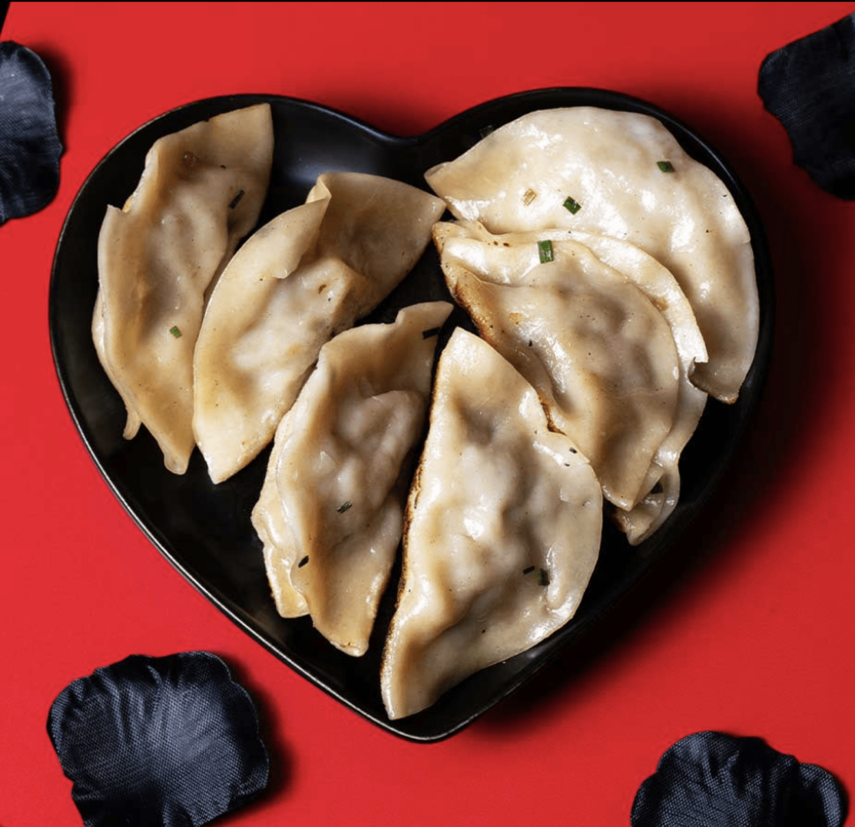 Dumplings on a heart plate against red background. (P.F. Changs)