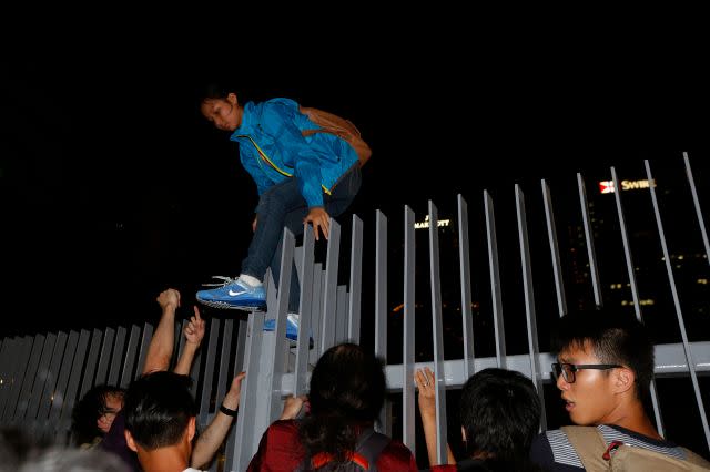 A protester climbs over a fence as she leaves after hundreds stormed into a restricted area at the government headquarters, after a rally ahead of the October 1 &quot;Occupy Central&quot; civil disobedience movement in Hong Kong September 26, 2014. 