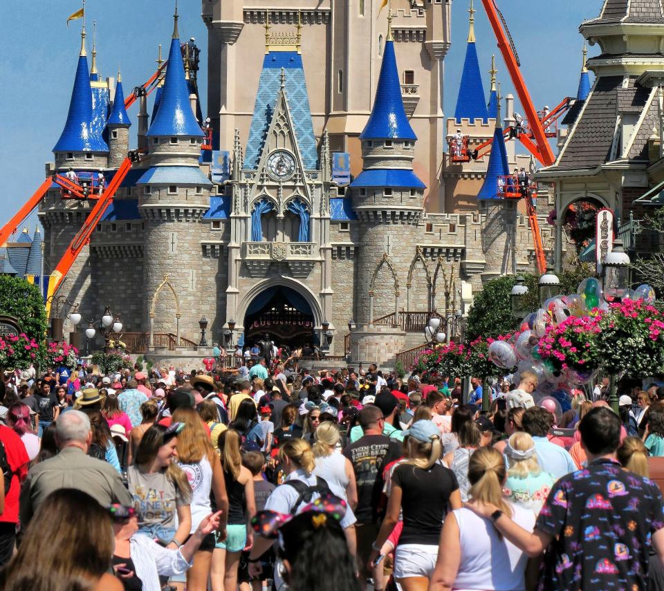 FILE - In this March 12, 2020, file photo, a crowd is shown along Main Street USA in front of Cinderella Castle in the Magic Kingdom at Walt Disney World in Lake Buena Vista, Fla. As Walt Disney World prepares to allow some third-party shops and restaurants to open at its entertainment complex later this week, it's posting a warning. While enhanced safety measures are being taken at Disney Springs, “an inherent risk of exposure to COVID-19 exists in any public place where people are present," the company said Monday, May 18, 2020, on a website for the entertainment complex.(Joe Burbank/Orlando Sentinel via AP, FIle)