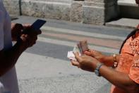 Jason Sanchez makes a transaction with cryptocurrency using the startup Fusyona near the seafront Malecon in Havana