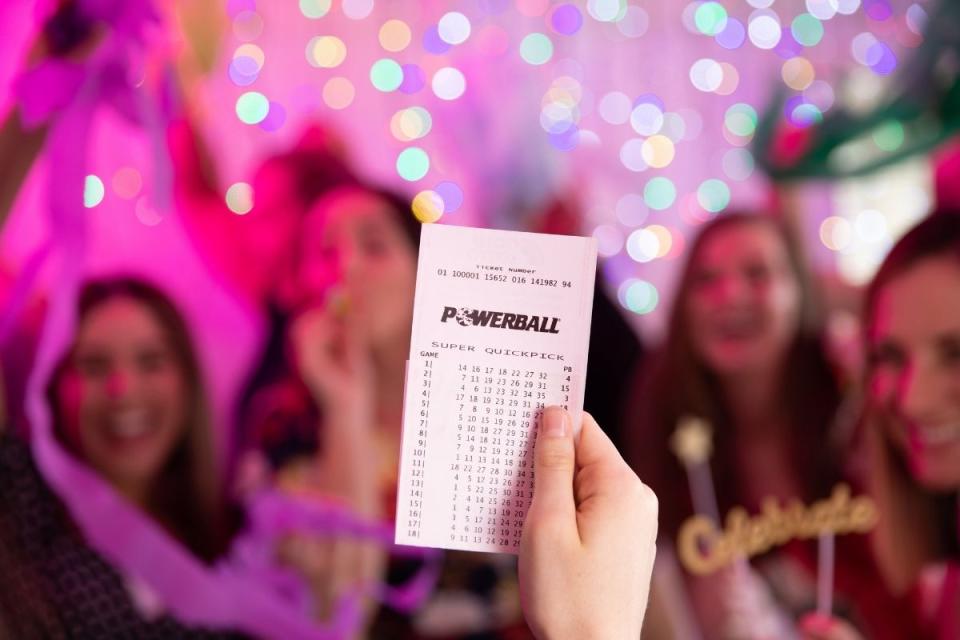 Person holds winning Powerball lottery ticket up in celebration. Source: The Lott