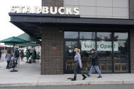 Customers walk past a sign that reads "We're Open!" at a Starbucks Coffee store in south Seattle, Tuesday, Oct. 27, 2020. Starbucks saw faster-than-expected recovery in the U.S. and China in its fiscal fourth quarter, giving it confidence as it heads into the holiday season. (AP Photo/Ted S. Warren)