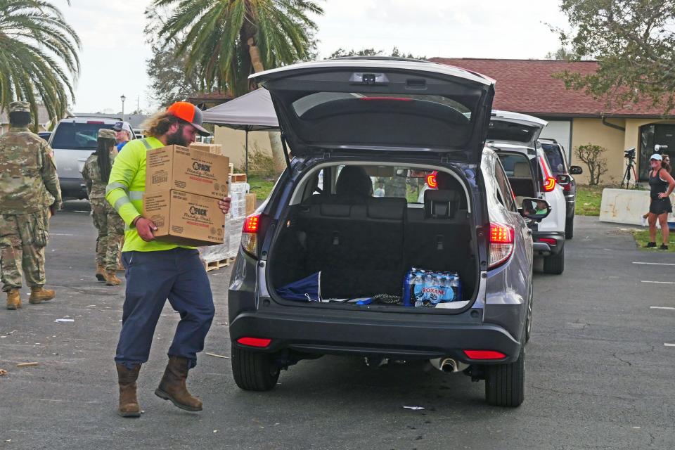 A volunteer delivers an MRE pack to a vehicle at the relief station at San Pedro Catholic Church.