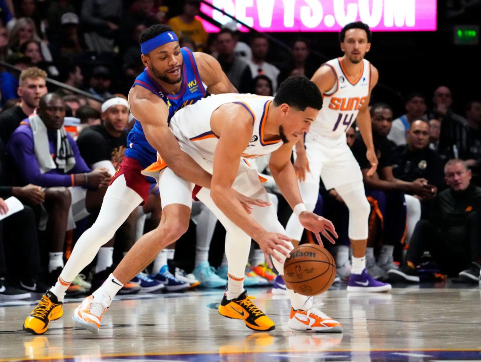 Apr 29, 2023; Denver, CO, USA; Denver Nuggets forward Bruce Brown (11) fouls Phoenix Suns guard Devin Booker (1) in the third quarter during Game 1 of the Western Conference Semifinals at Ball Arena. Mandatory Credit: Rob Schumacher-Arizona Republic