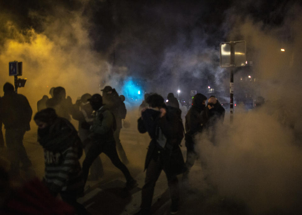 People run away from team gas during a demonstration in Paris, Thursday, Dec. 5, 2019. The Eiffel Tower shut down, France's high-speed trains stood still and tens of thousands of people marched through Paris and other cities Thursday, in a massive and sometimes chaotic outpouring of anger at the government's plan to overhaul the retirement system. (AP Photo/Rafael Yaghobzadeh)