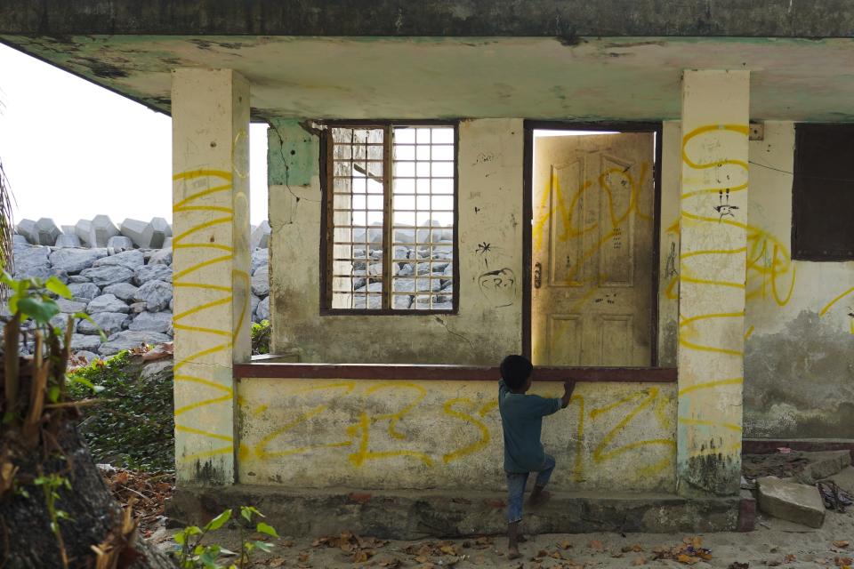 A boy plays on a home near a newly built sea wall in Kochi, Kerala state, India, on March 4, 2023, that was abandoned after the 2021 Cyclone Tauktae. The house remains a constant reminder of the harrowing aftermath of the cyclone's sea surge, displacements and relief camps. (AP Photo)