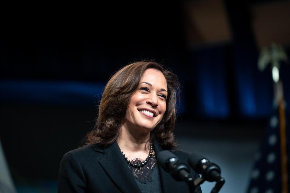 Kamala Harris smiling while standing in front of microphones.