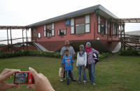 Tourists pose with an upside-down house in Tamparuli in Malaysia's state of Sabah on Borneo island September 17, 2012. Built for tourist attraction, the traditional Sabah village house was built with everyday households items like computer, refrigerator, sofa sets, dining table and beds - but all items are upside down. REUTERS/Bazuki Muhammad (MALAYSIA - Tags: SOCIETY TRAVEL) - RTR3832O