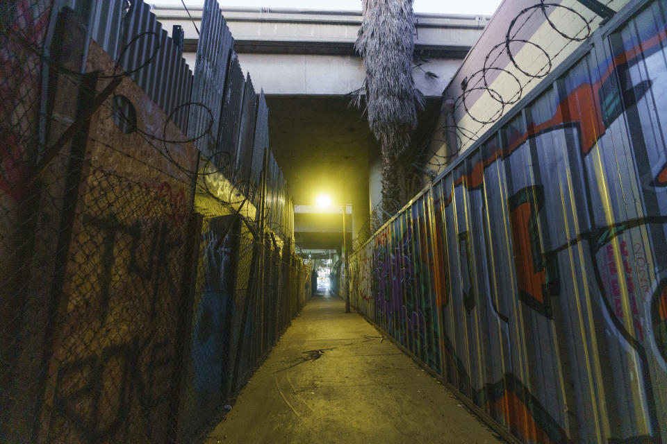 A light shines at an underpass is under Interstate 10 between two warehouses in Los Angeles Friday, Dec. 8, 2023. (AP Photo/Damian Dovarganes)