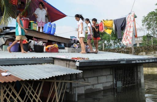 A family gathers on the roof of their home in Calumpit town, north of Manila. Philippine authorities have scrambled to provide food and other emergency provisions to more than two million people affected by widespread flooding, as the death toll rose to 66