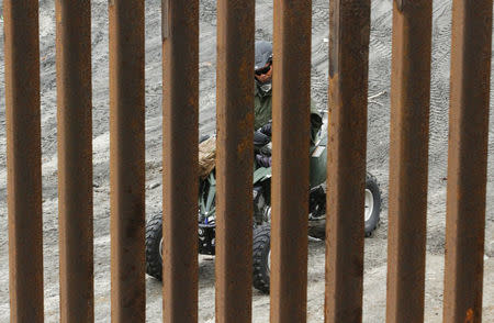 A U.S. Border Patrol agent is seen through the border fence between the United States and Mexico as photographed from Tijuana, Mexico February 11, 2017. REUTERS/Jorge Duenes